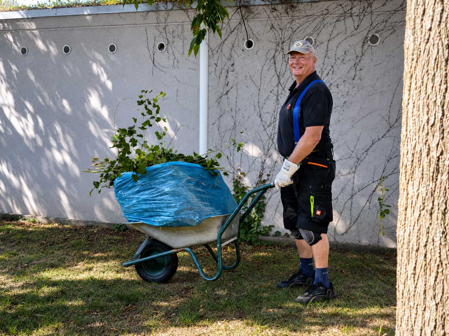 Haustechniker bei Reisdorf arbeitet im Außengelände am Standort Dresdner Tor Süd mit Schubkarre, Gartenmaterial und Arbeitskleidung.
